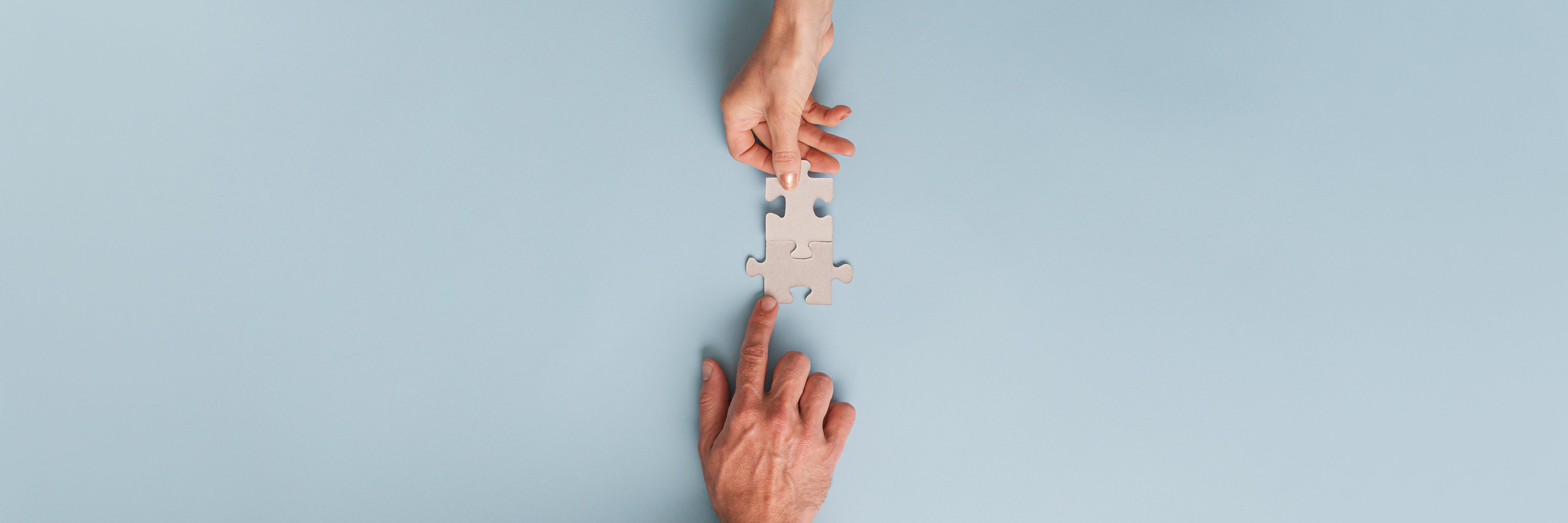 Male and Female Hands Putting Puzzle Pieces Together